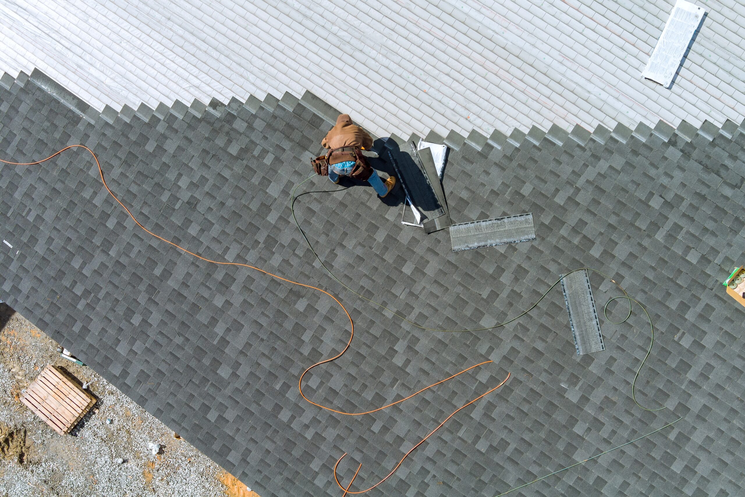 Aerial top view a asphalt shingles installation on the roof roofer is nailing asphalt shingles to roofing construction